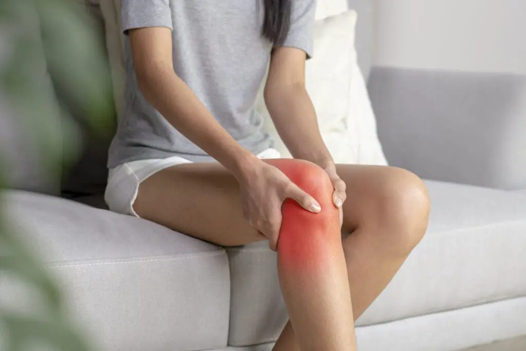 woman holding knee. knee is lit up red to indicate pain or discomfort