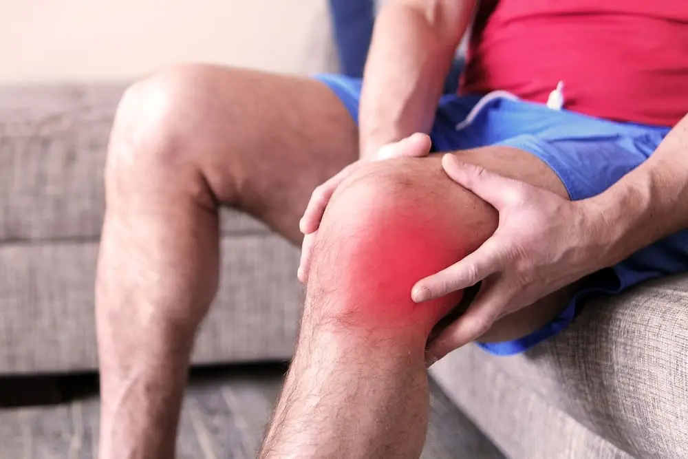 image of a man holding his knee. his knee is lit up red to indicate pain and discomfort